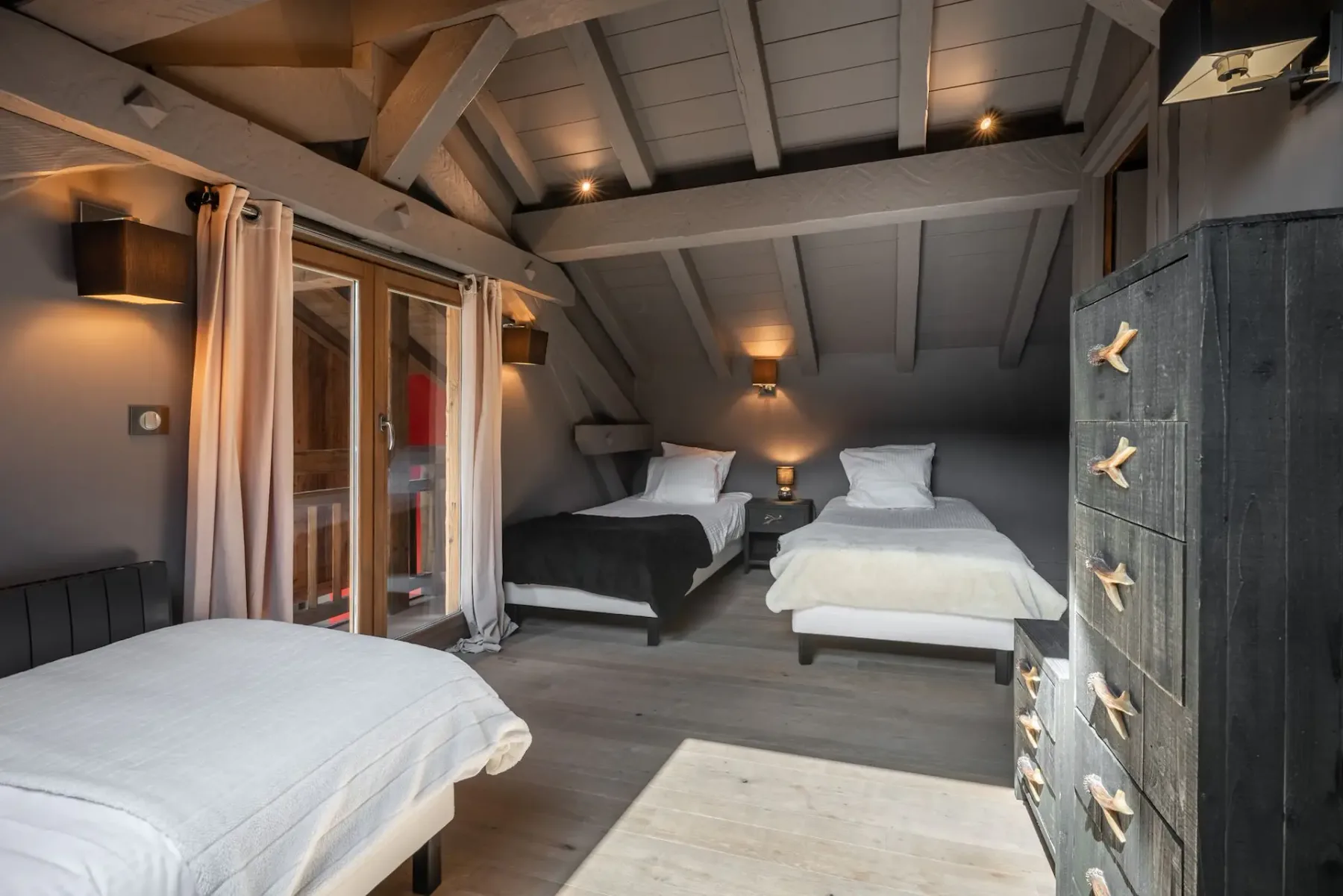 Un dormitorio acogedor con suelo y techo de madera, paredes oscuras, una cama con manta de pelo y cojines decorativos, y lámparas de pared.