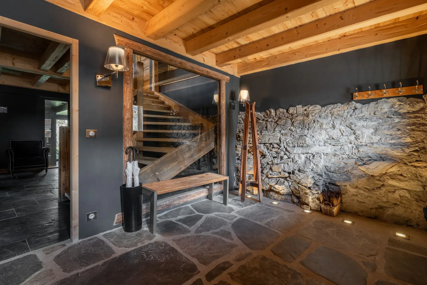 Un interior rústico con una escalera de madera junto a una pared de piedra vista.