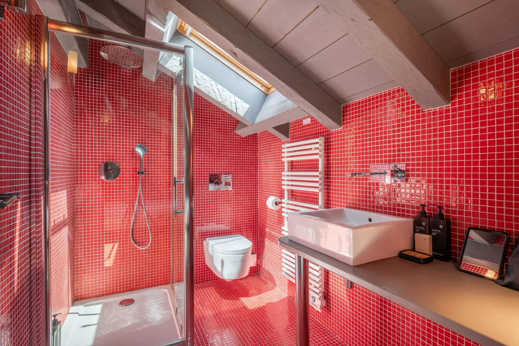 Un baño con ducha y lavabo bajo un techo inclinado.
