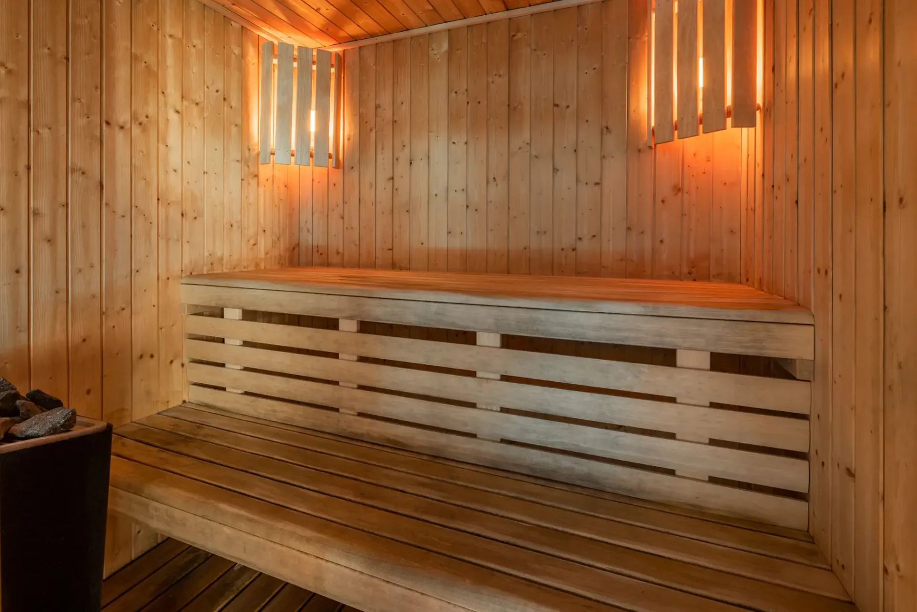 Una sauna de madera con asientos escalonados y luces verticales cálidas.