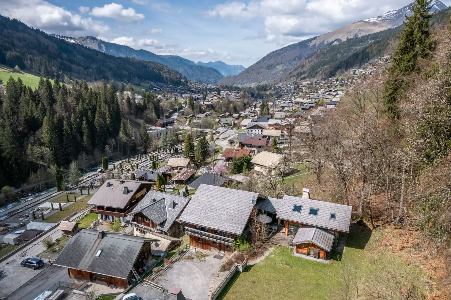 Un pueblo en la ladera se extiende por un valle de montaña bajo un cielo parcialmente nublado.