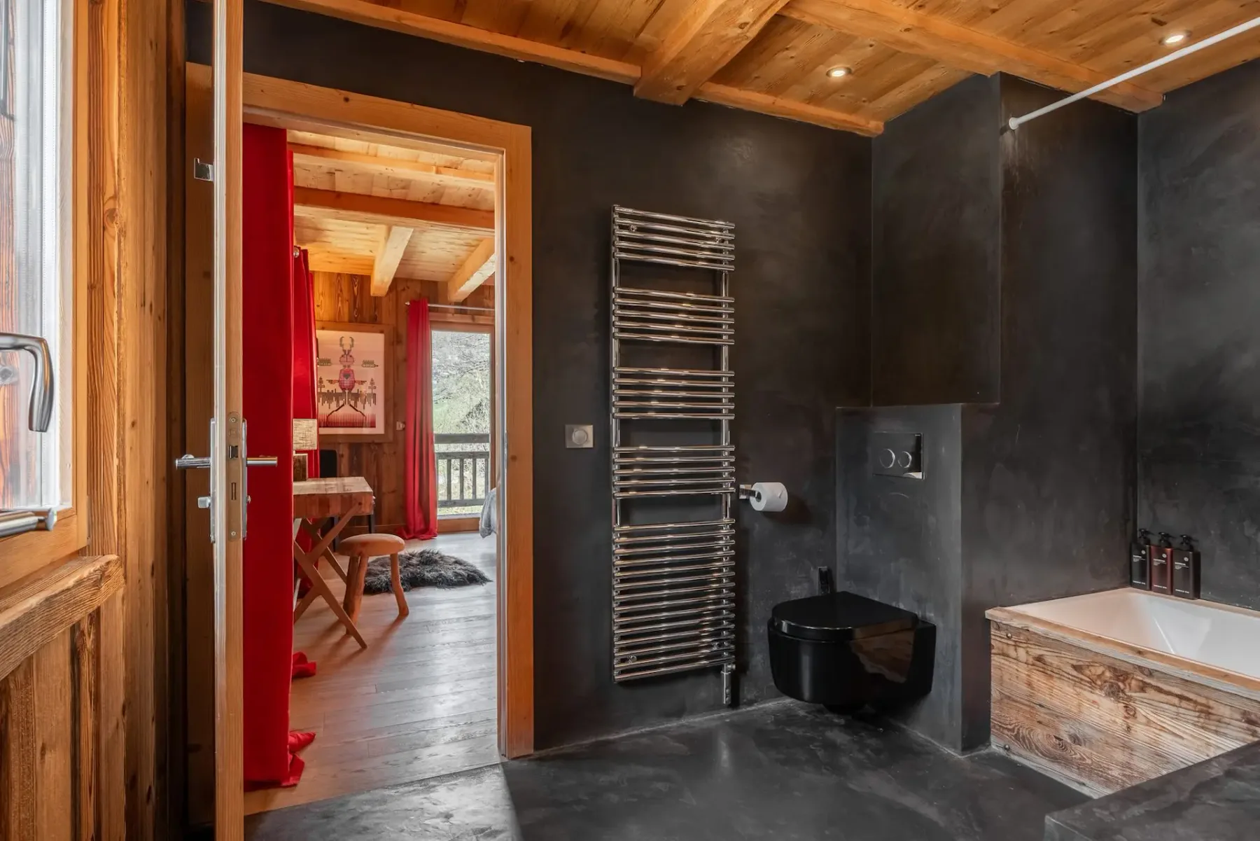 Un baño oscuro con un toallero calefactable y una bañera.
