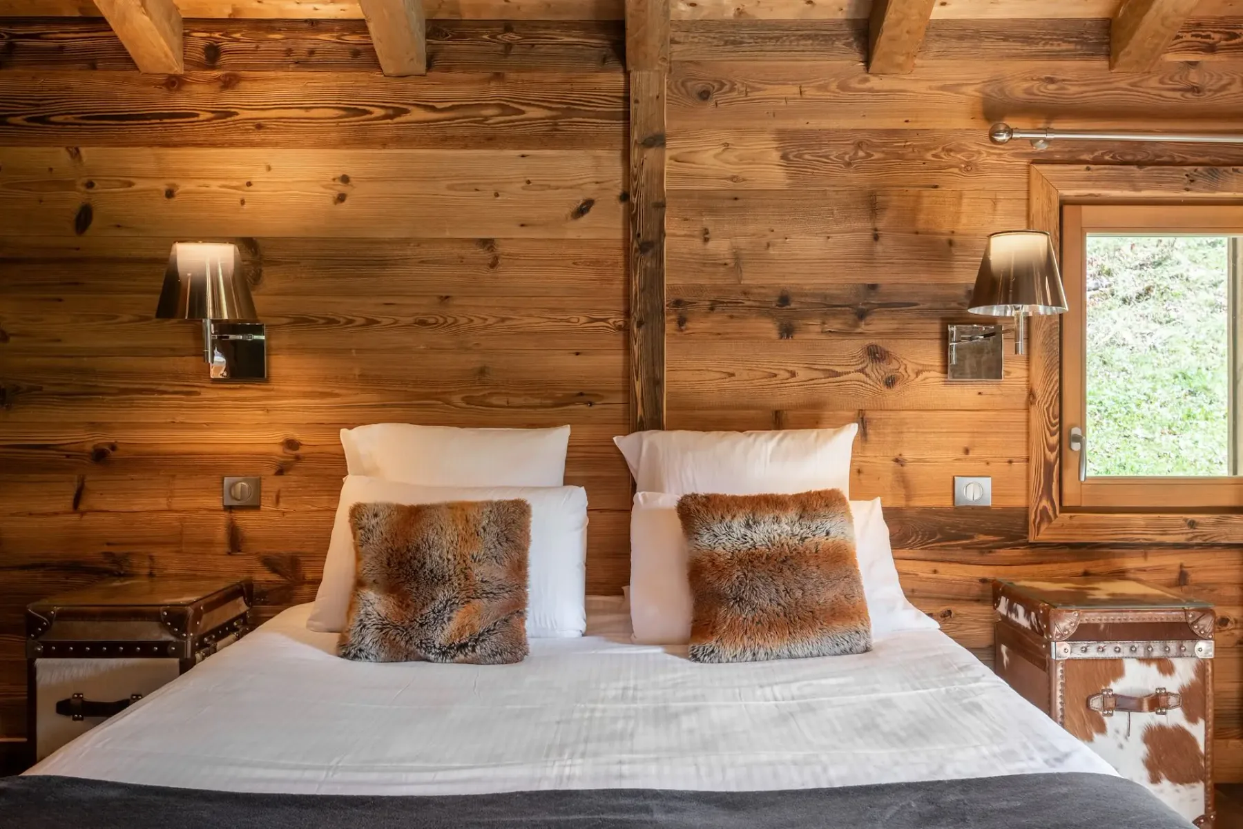 Un dormitorio con una cama grande, cojines estampados y un interior de madera.
