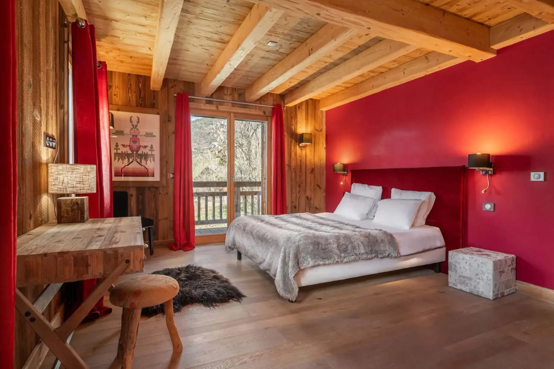Un dormitorio con una cama, una pared roja y vigas de madera en el techo.