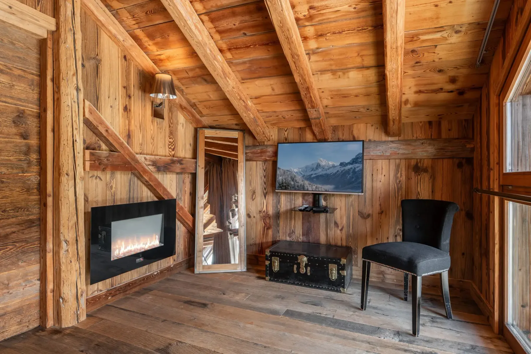 Una sala revestida de madera con un televisor montado en la pared y asientos.