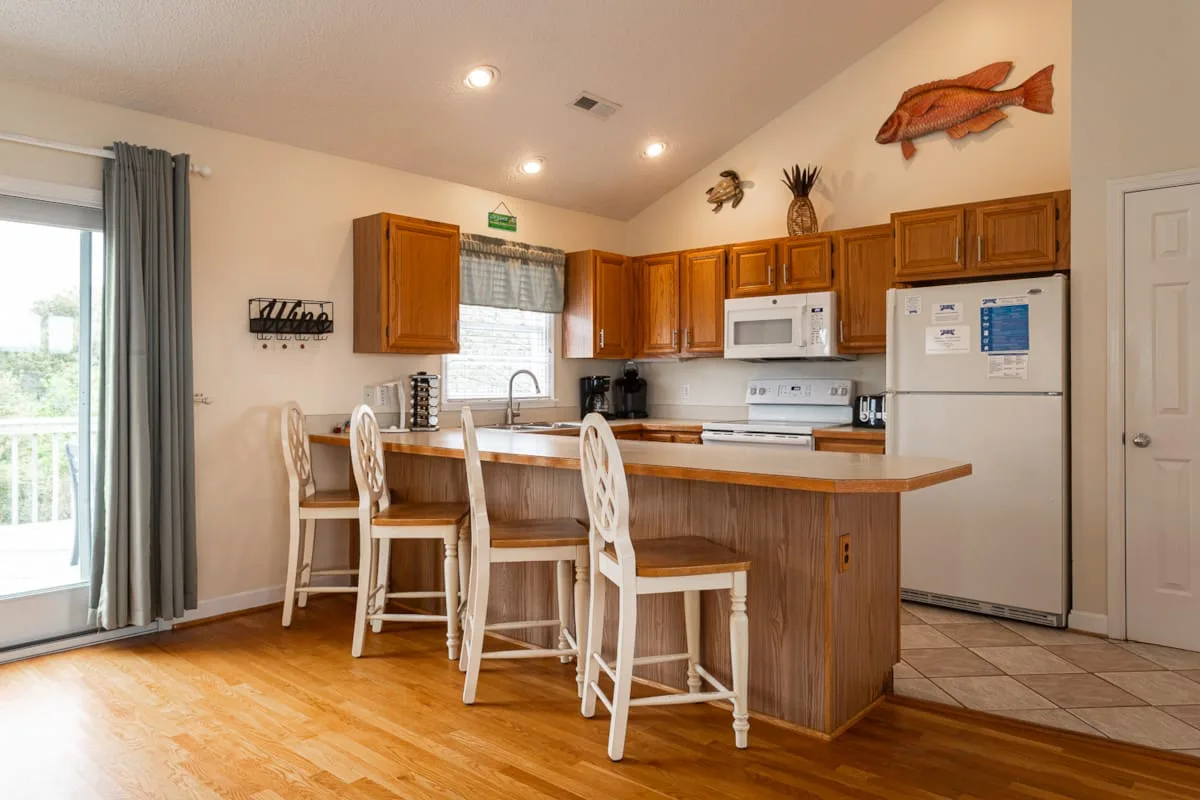 Una cocina luminosa con gabinetes de madera, una barra y taburetes.