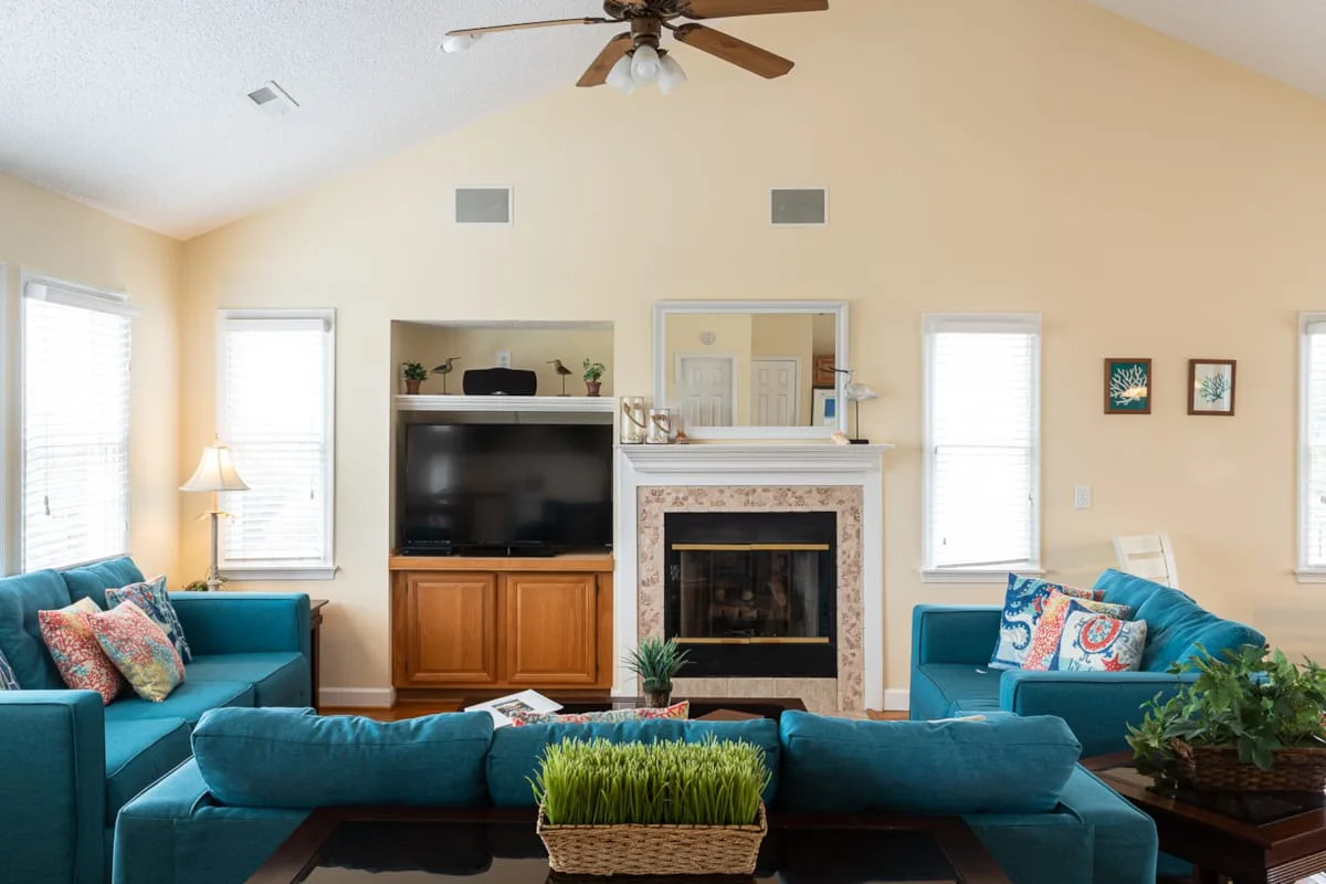 A living room with teal seating, a television, and a fireplace.