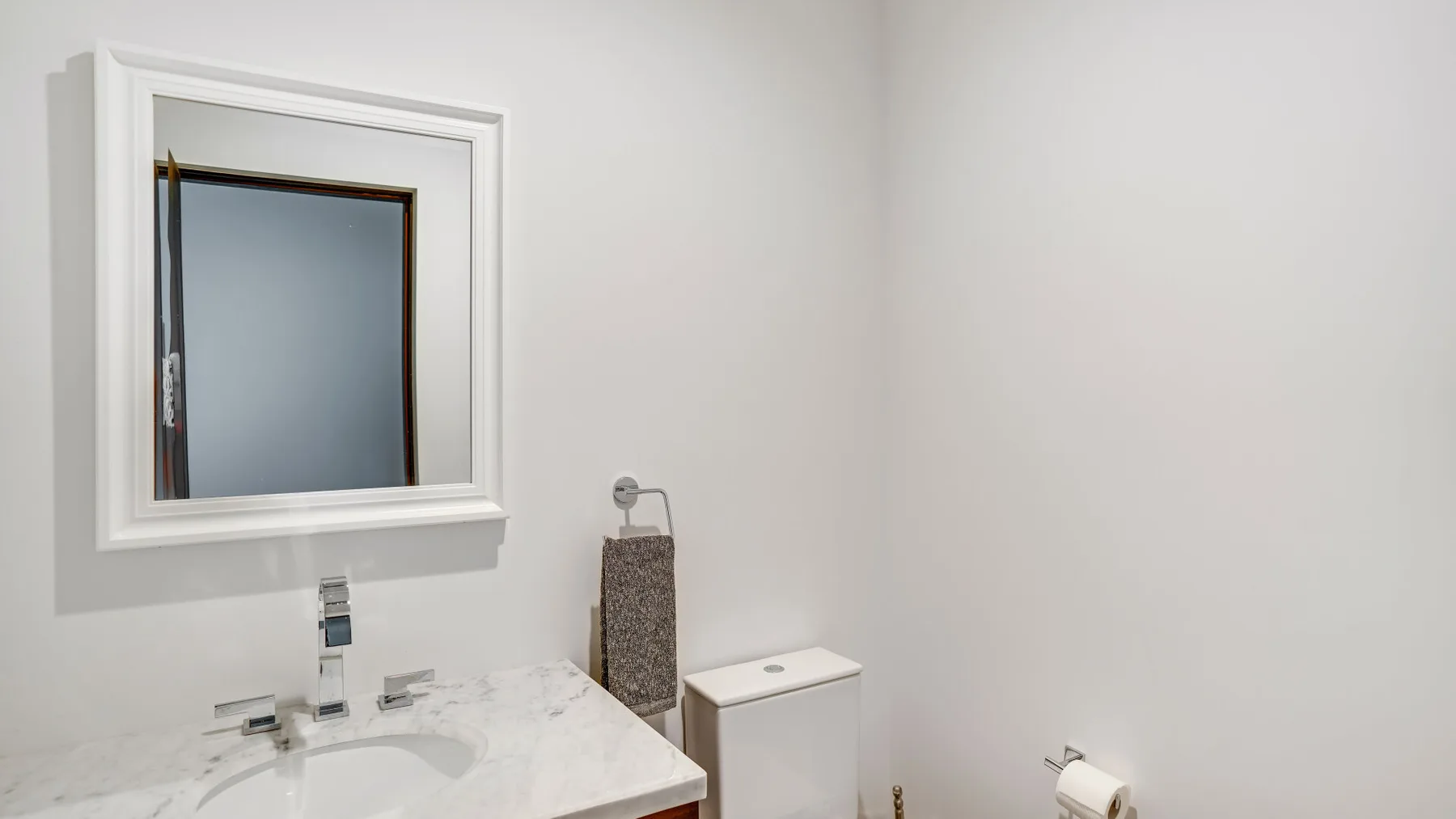 A bathroom vanity with a mirror, sink, and toilet.