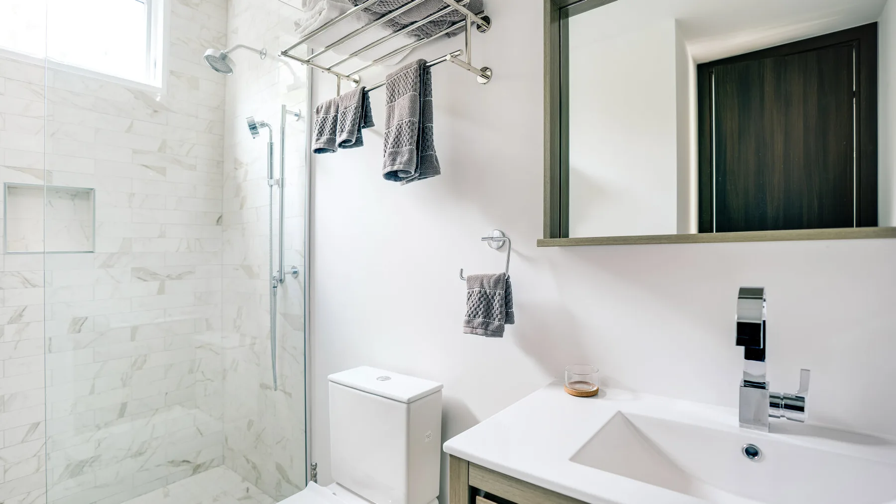 A bright bathroom with a tiled shower and a white sink vanity.