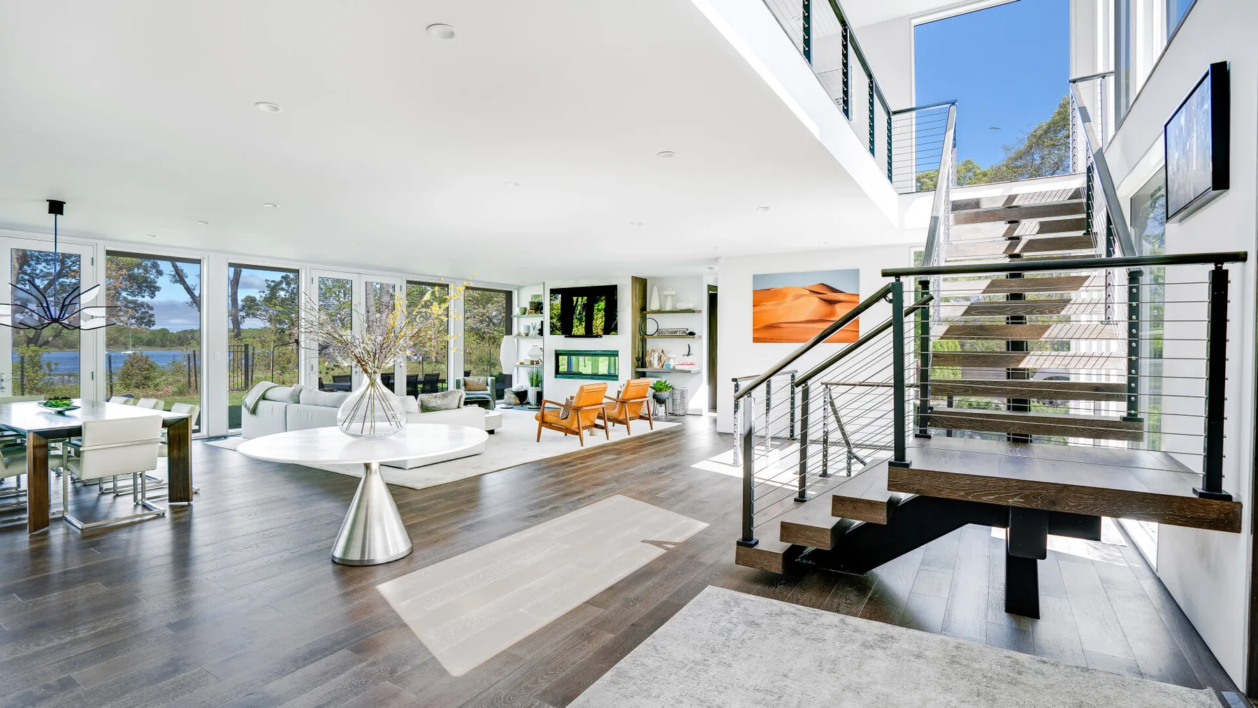 A bright open-plan living and dining area with large windows and a staircase.