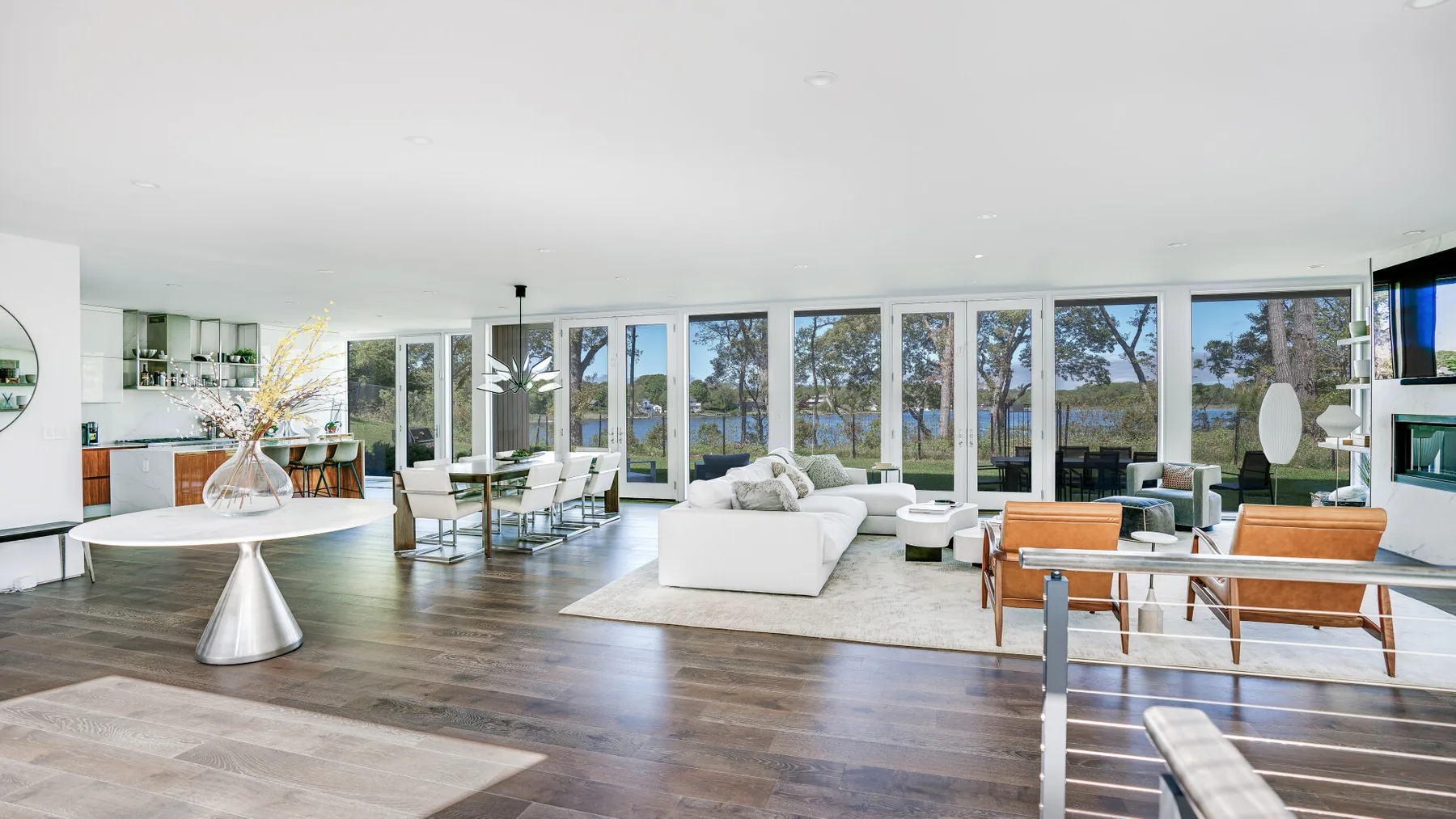An open living and dining area has large windows overlooking the water.