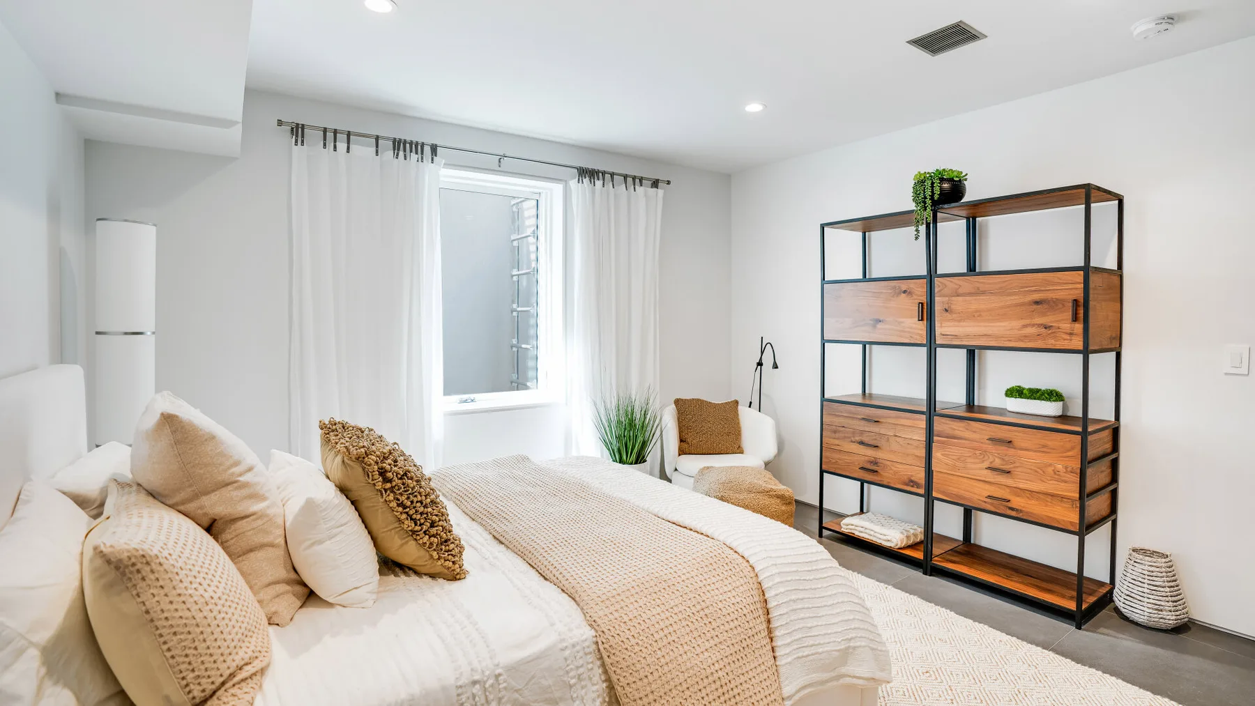 A bright bedroom with a bed beside a window and open shelving.