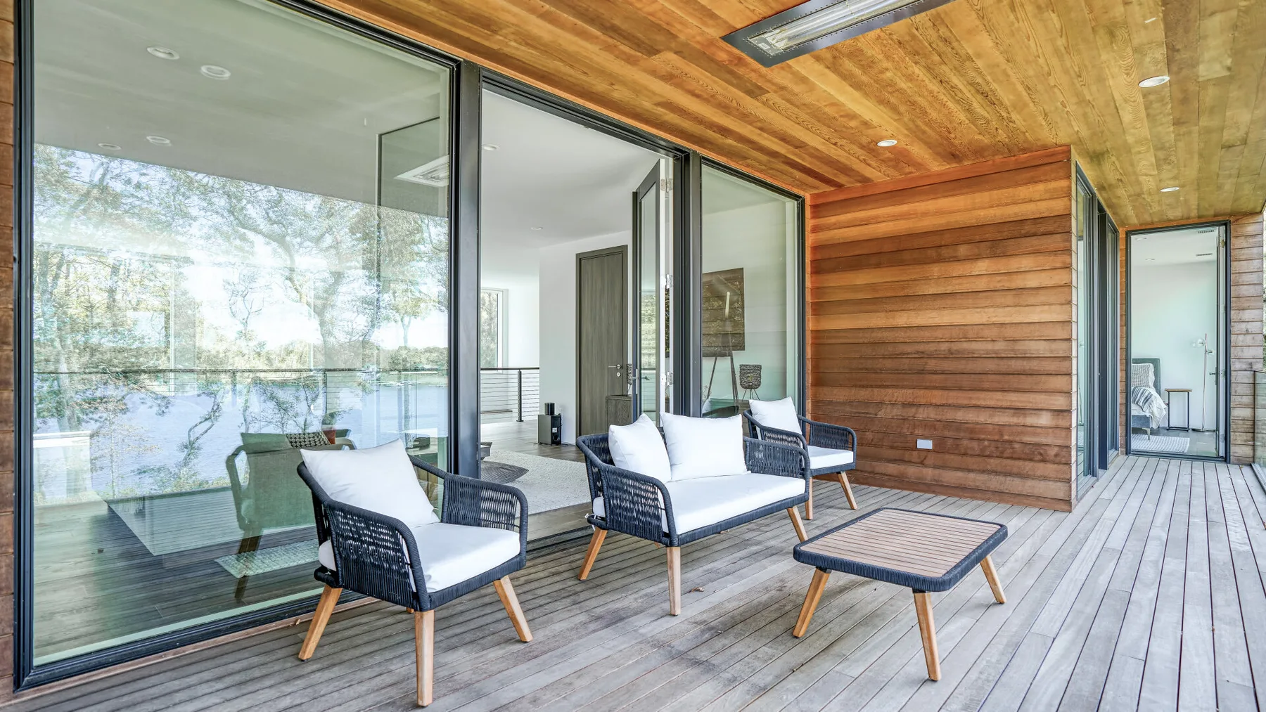 A covered outdoor seating area with glass doors and a wood-paneled wall.