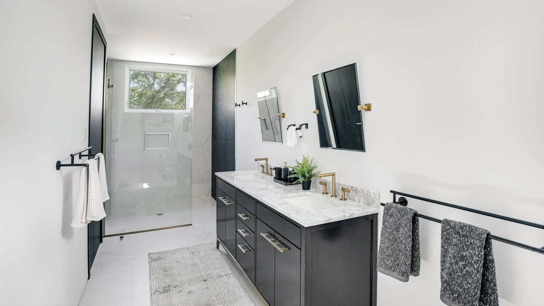 A bright bathroom with a walk-in shower and a long vanity.