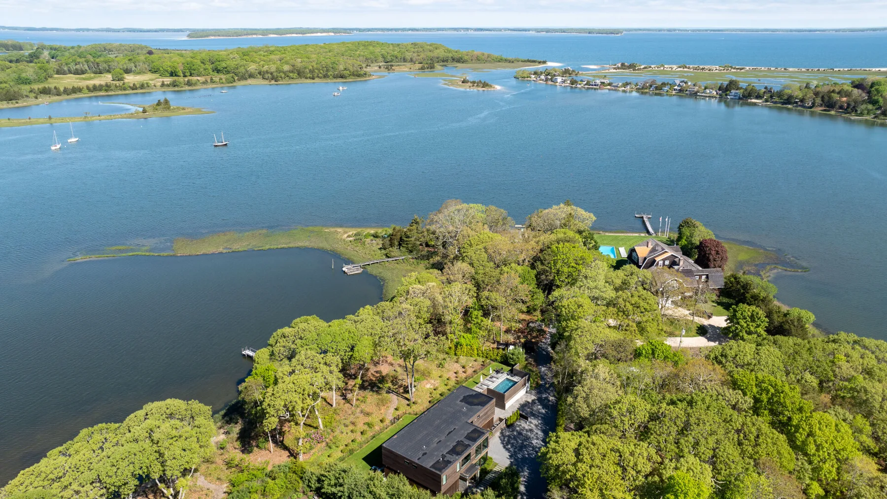 An aerial view shows a wooded property beside a broad blue lake.