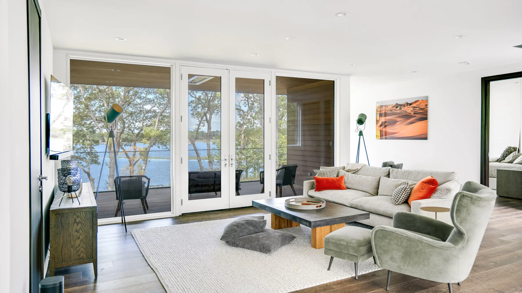 A bright living room with seating, a coffee table, and large windows overlooking the water.