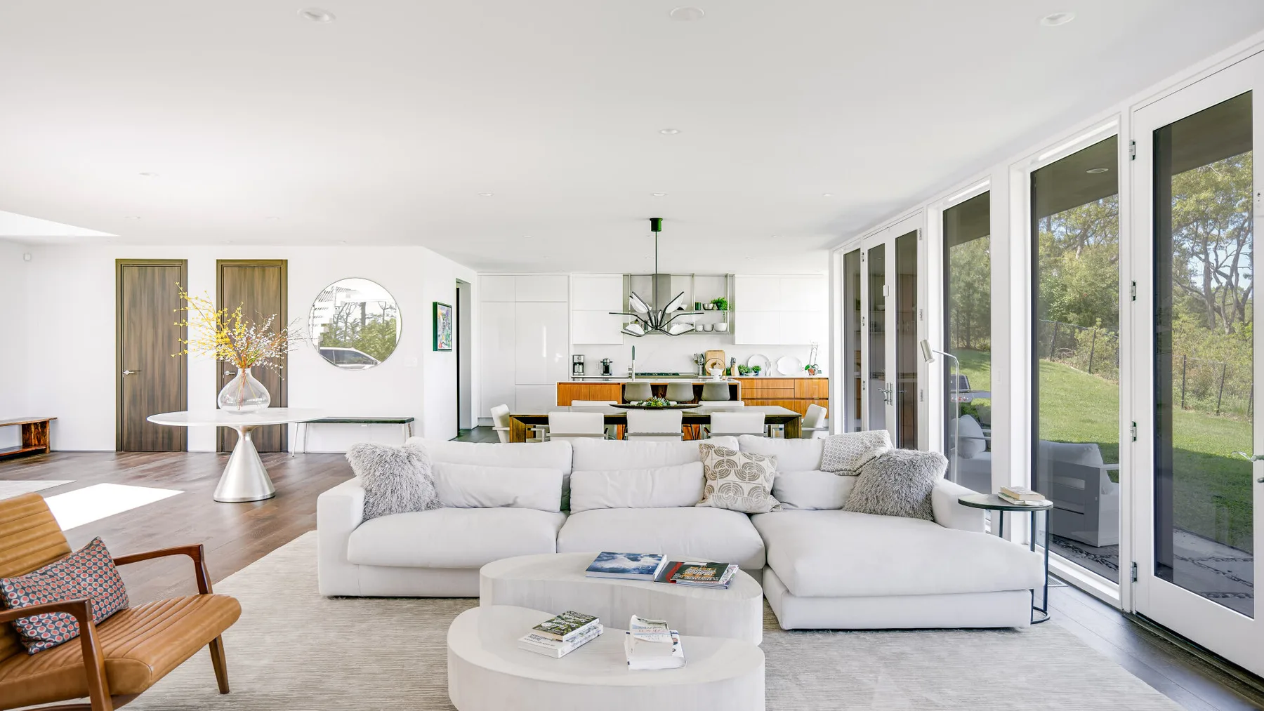 A bright living room with white seating beside large glass doors and windows.