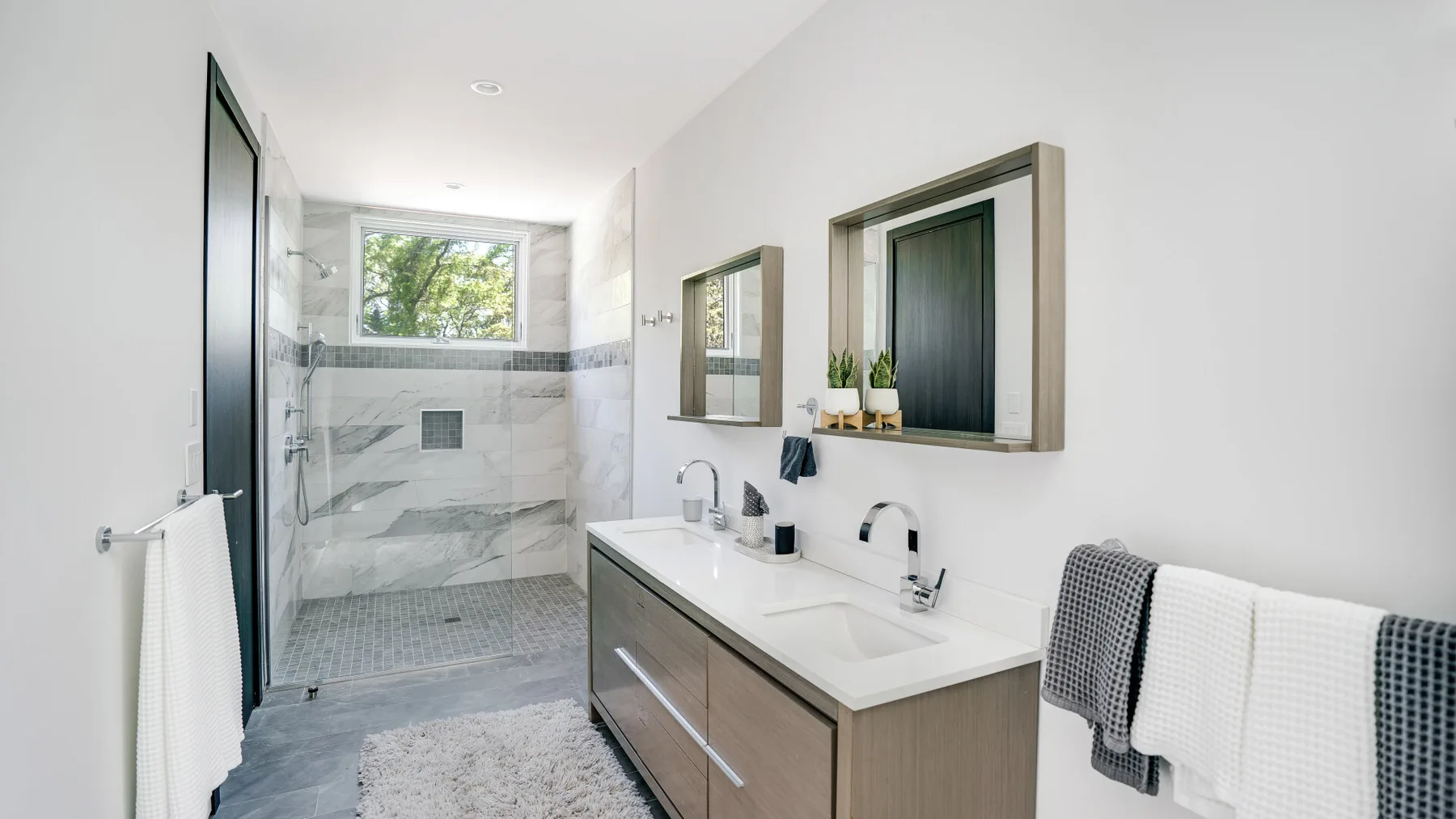 A bright bathroom with a walk-in shower and a double sink vanity.
