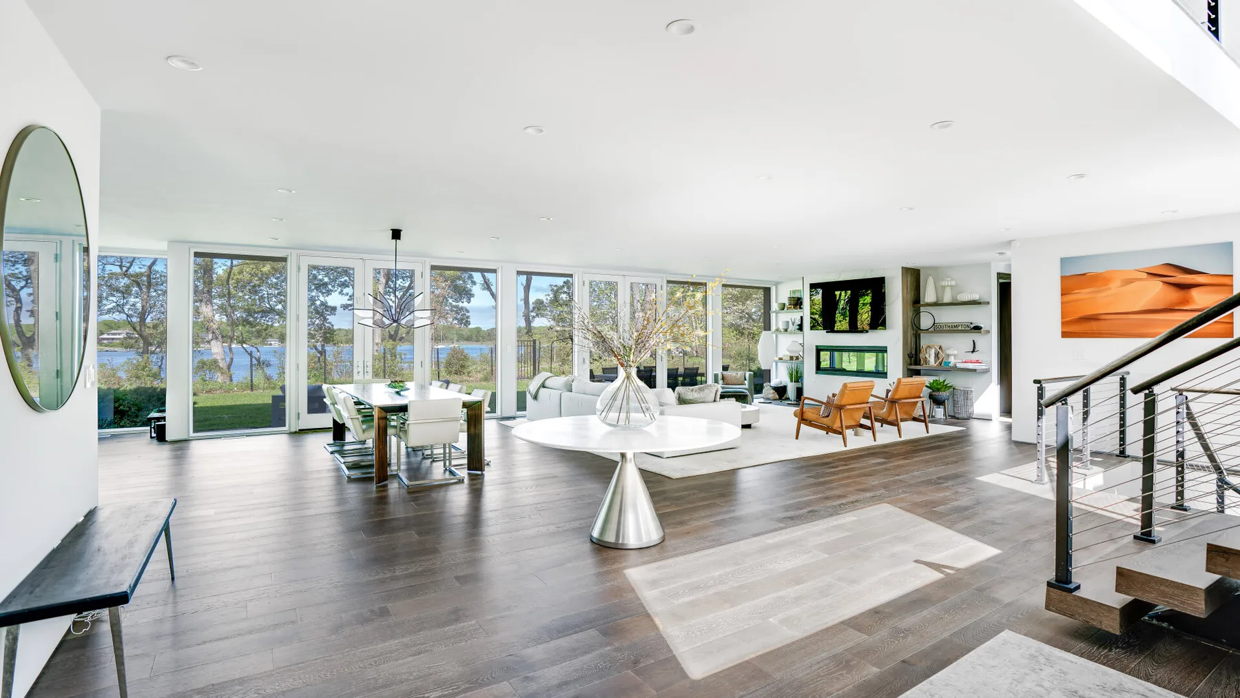 A bright open living and dining area with large windows overlooking the water.