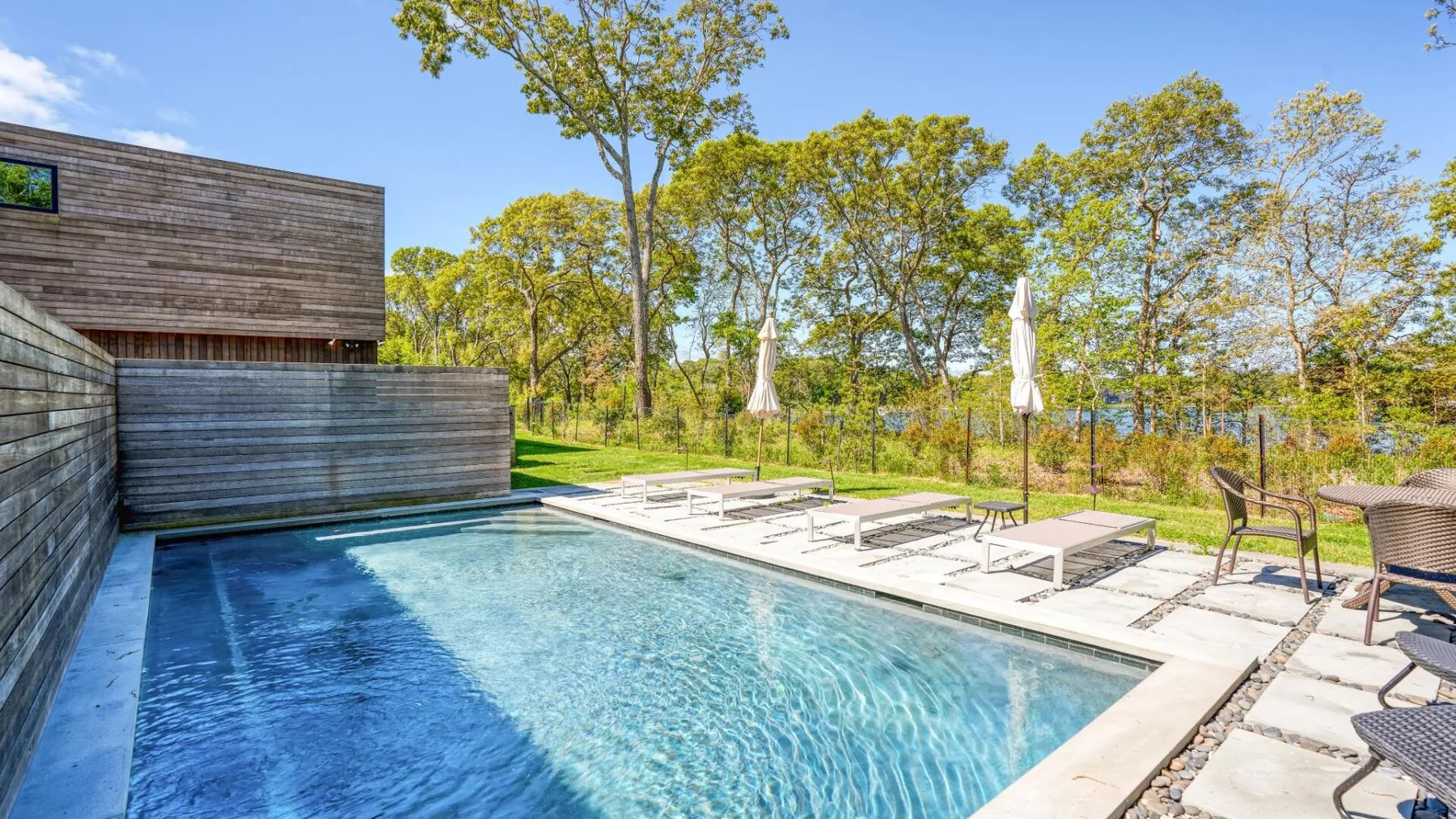 Una piscina al aire libre está junto a un edificio de madera y sillas de descanso.