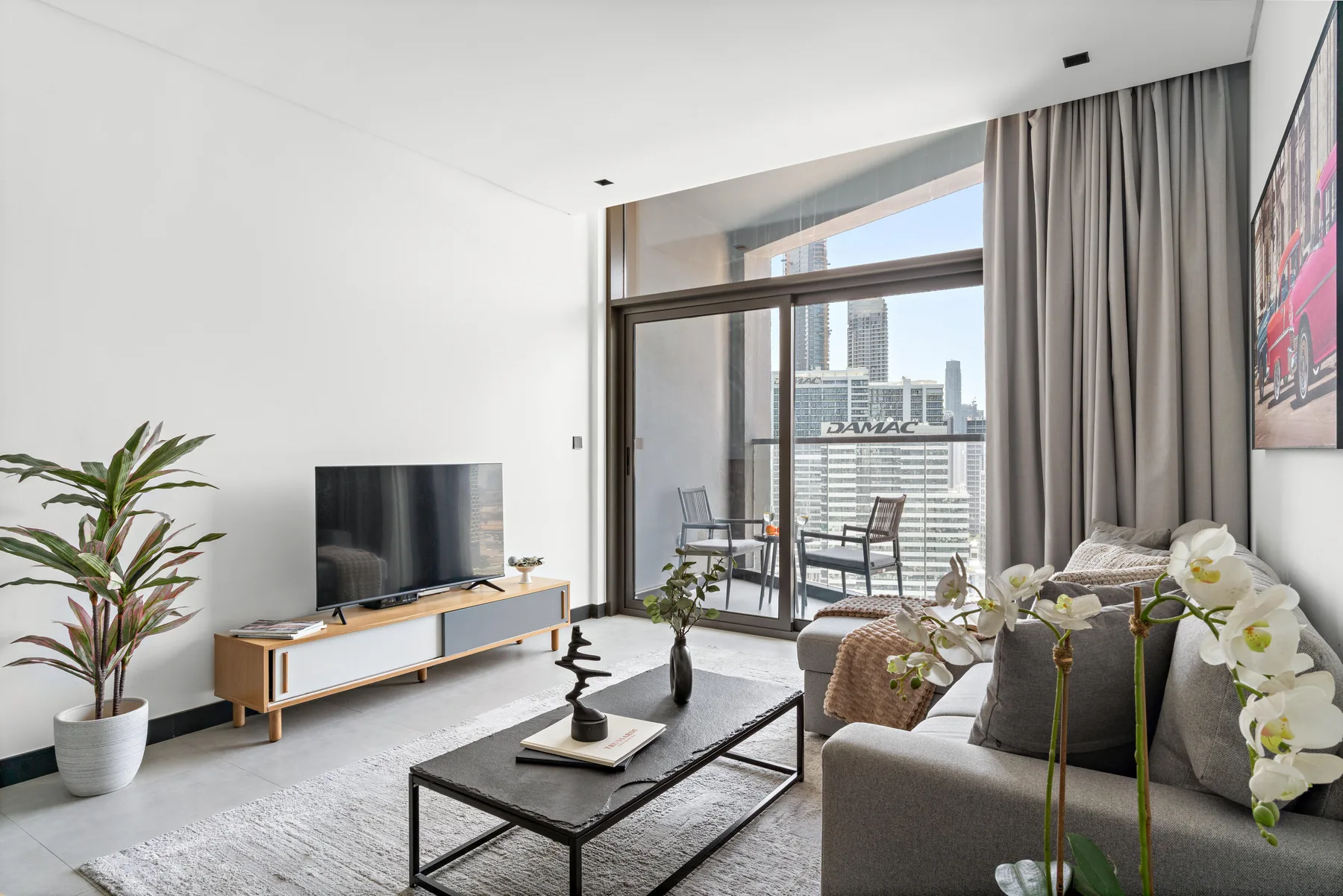 Una sala luminosa con televisor, asientos y grandes ventanales con vistas a la ciudad.
