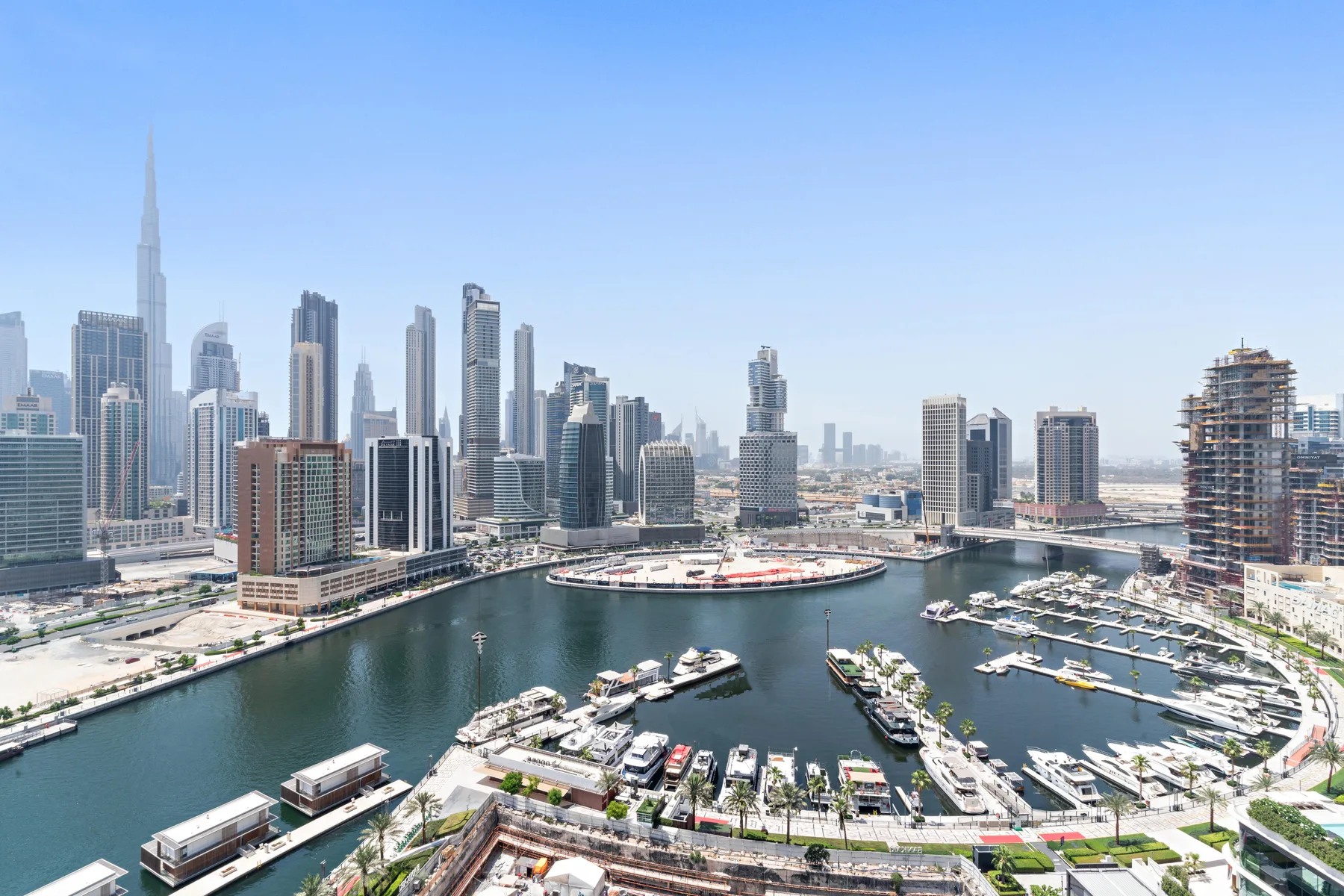 A city skyline rises behind a marina filled with boats.