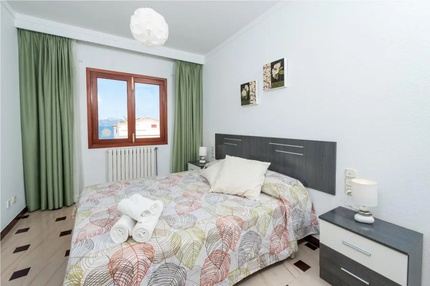 A bedroom with a patterned bedspread and green curtains beside the window.
