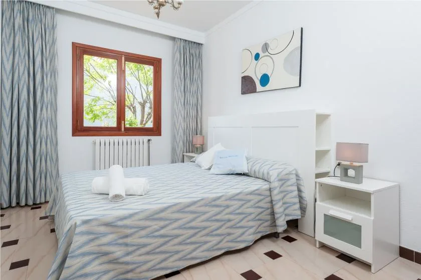 A bedroom with a neatly made bed beneath a window.