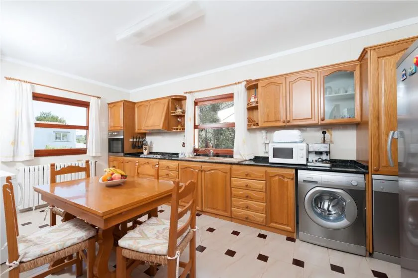A kitchen and dining area with wooden cabinets, a table, and appliances.