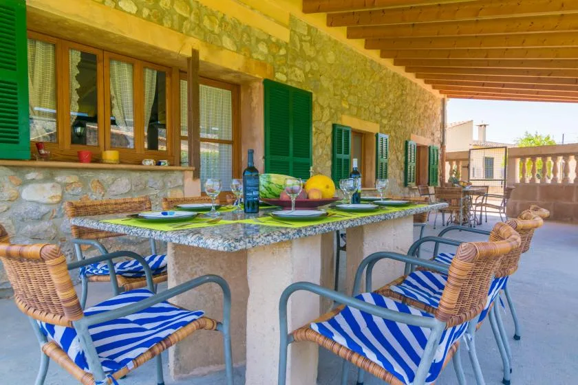Comedor exterior cubierto con una mesa larga y asientos a rayas.