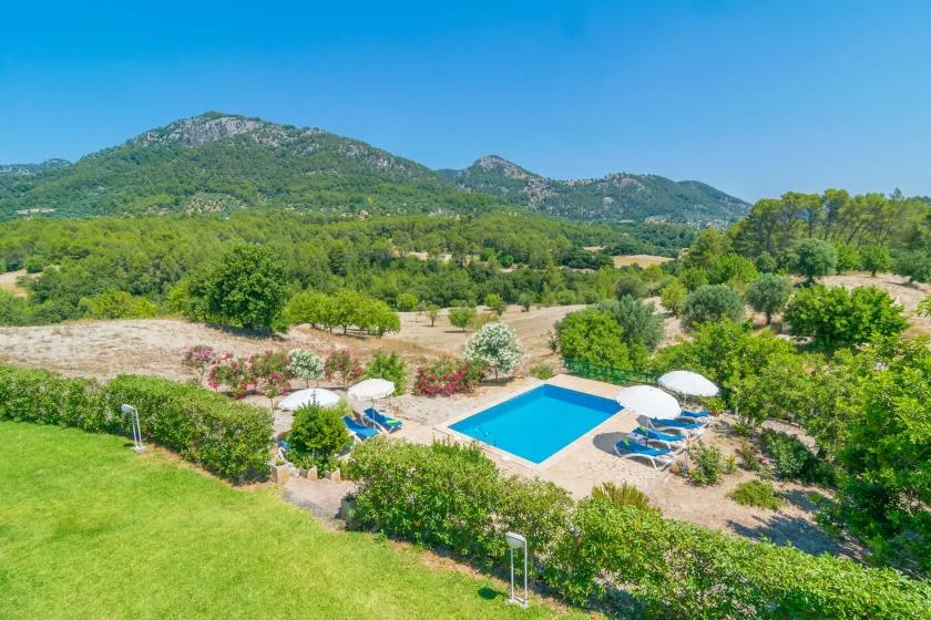 Una piscina está rodeada de jardines, con colinas verdes al fondo.