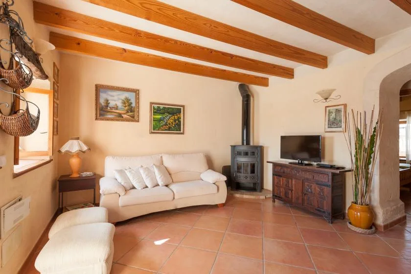 Una sala de estar con sofá, televisor y techo con vigas de madera.