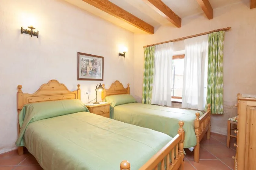 Un dormitorio con dos camas de madera vestidas con ropa de cama verde claro.
