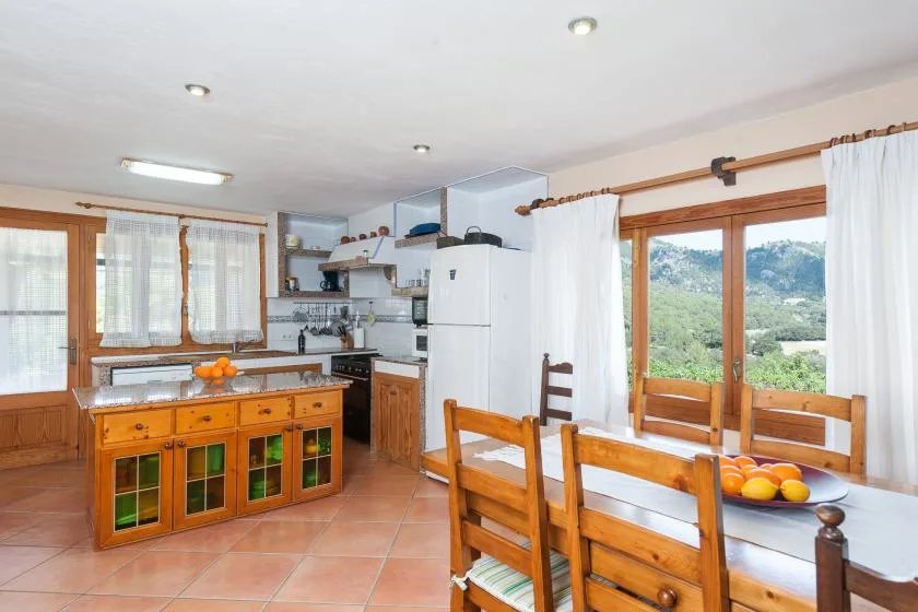 Una cocina y comedor con muebles de madera y ventanas con vistas a la vegetación.