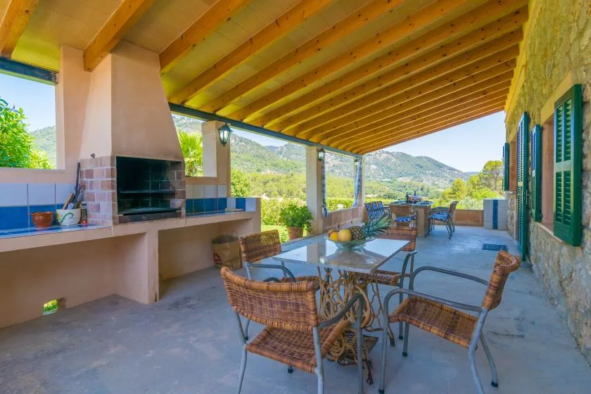 Una zona de comedor exterior cubierta con una mesa y sillas frente a las colinas.