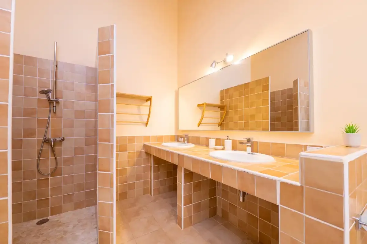 Un baño alicatado con ducha y un largo lavabo bajo un espejo.
