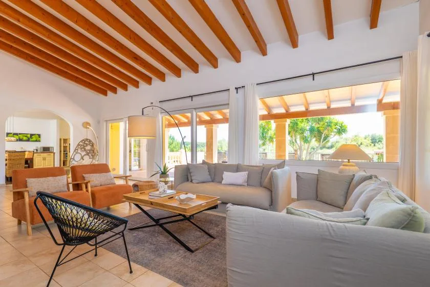 Una sala luminosa con asientos alrededor de una mesa de centro junto a grandes ventanas.