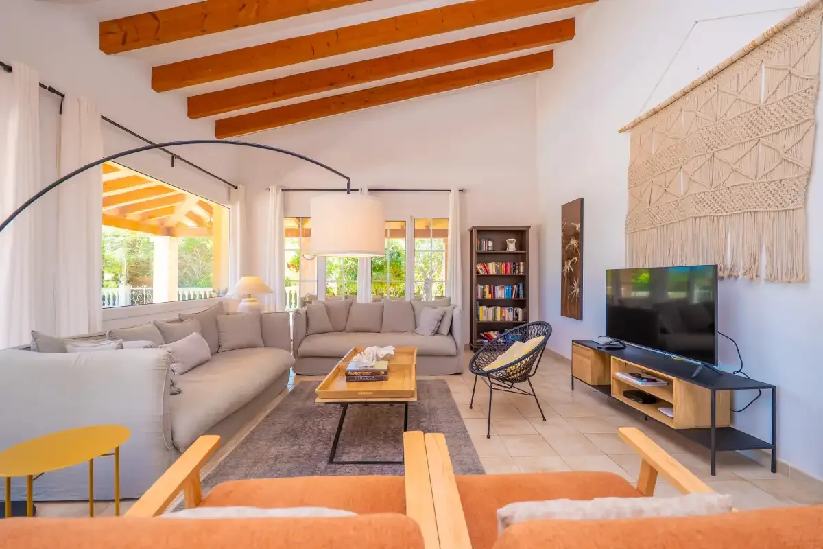 Una sala de estar luminosa con asientos, un televisor y vigas a la vista.