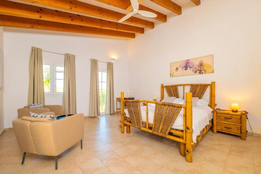 Un dormitorio con una cama, una zona de estar y vigas de madera expuestas en el techo.