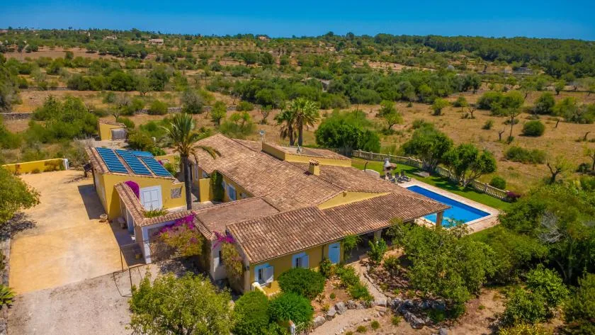 Vista aérea de una casa rural con piscina y vegetación alrededor.