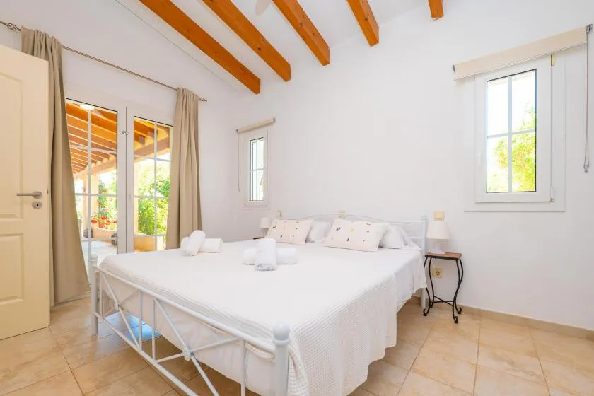 Un dormitorio luminoso con una cama grande y vigas de madera vistas en el techo.