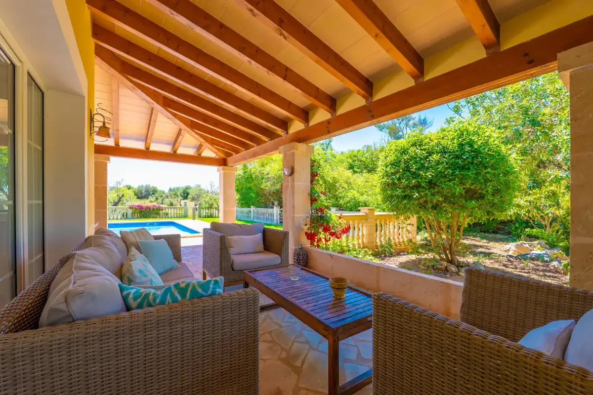 Un patio cubierto tiene asientos al aire libre y vistas al jardín y la piscina.
