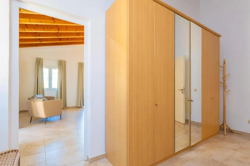 Un armario de dormitorio con puertas de espejo está junto a una puerta abierta a una zona de estar.