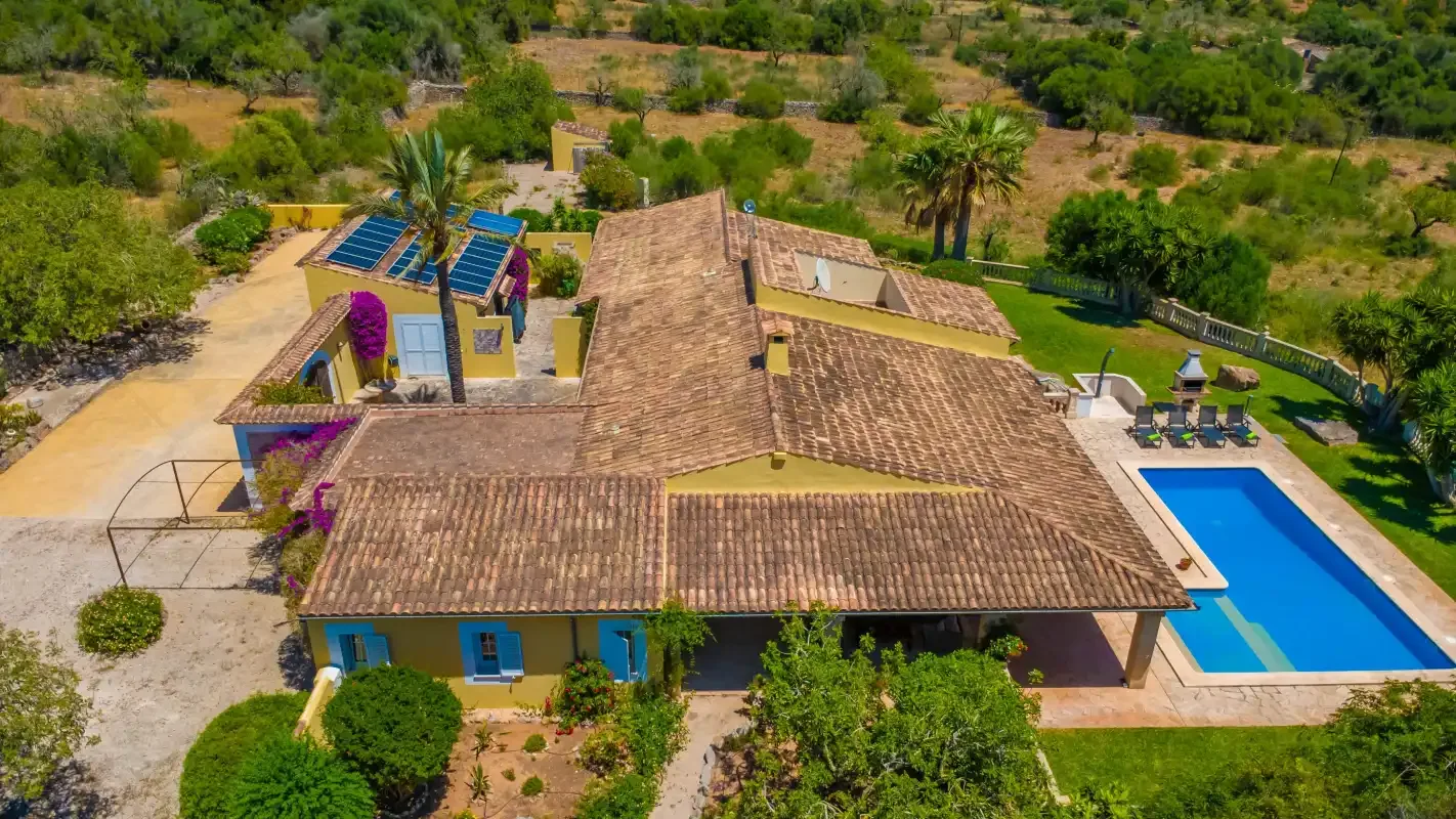 Vista aérea de una casa con piscina rodeada de zonas verdes.