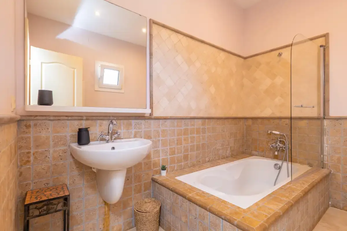 Un baño alicatado con bañera y lavabo suspendido.