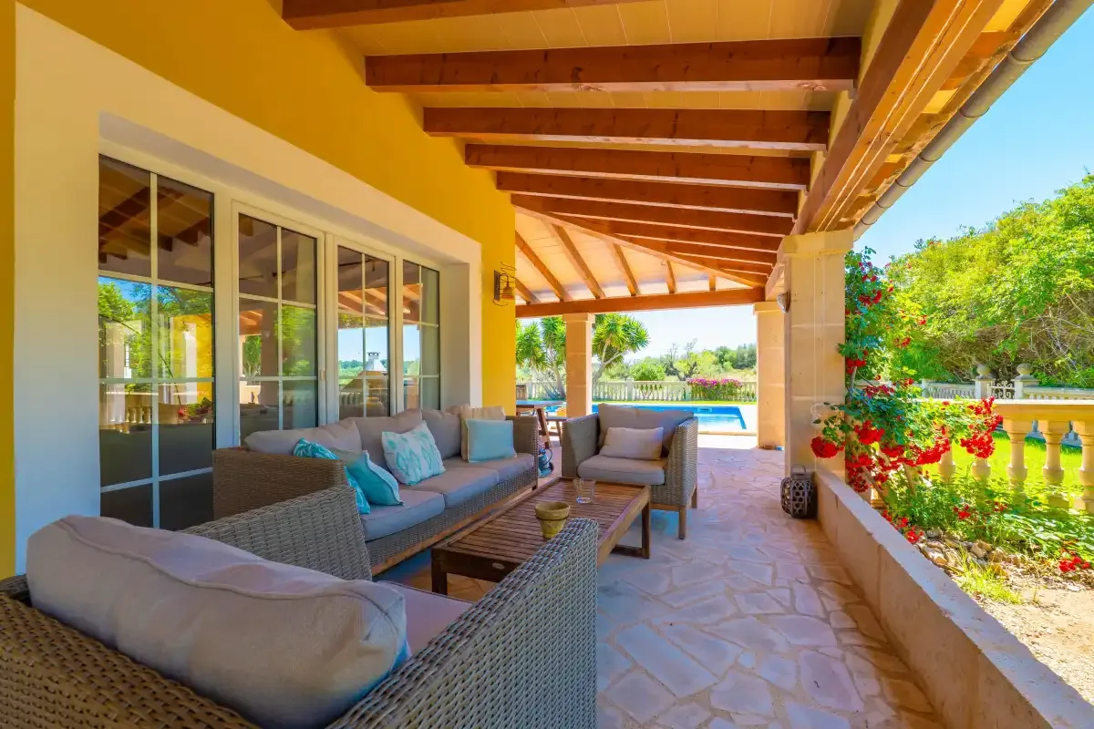 Un patio cubierto con asientos al aire libre y vistas al jardín.