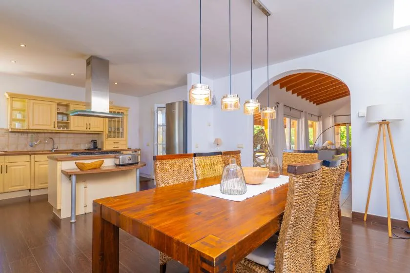 Un comedor de planta abierta con una mesa de madera junto a una cocina.