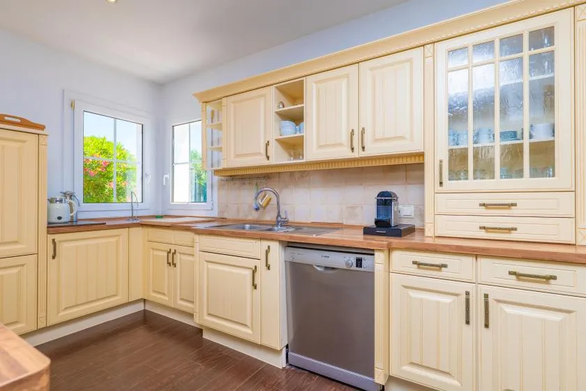 Una cocina luminosa con gabinetes claros, encimera y lavavajillas de acero inoxidable.