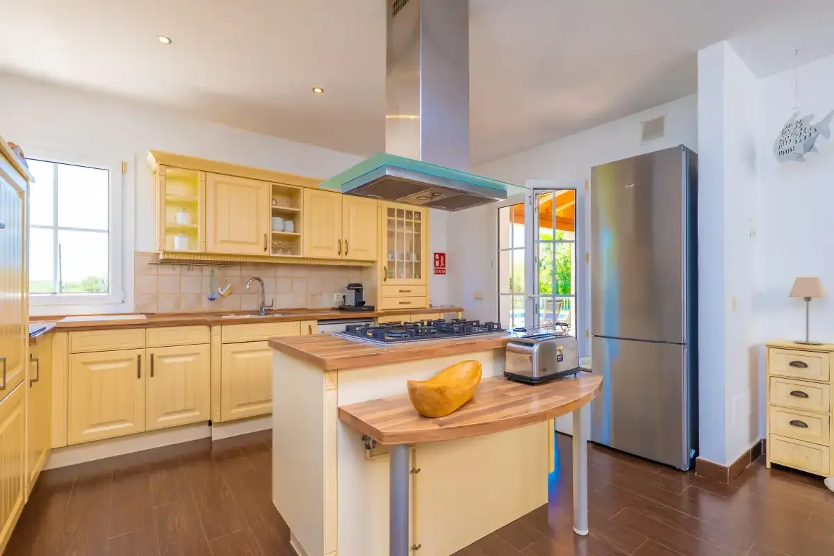 Una cocina luminosa con gabinetes de madera clara y una isla central.