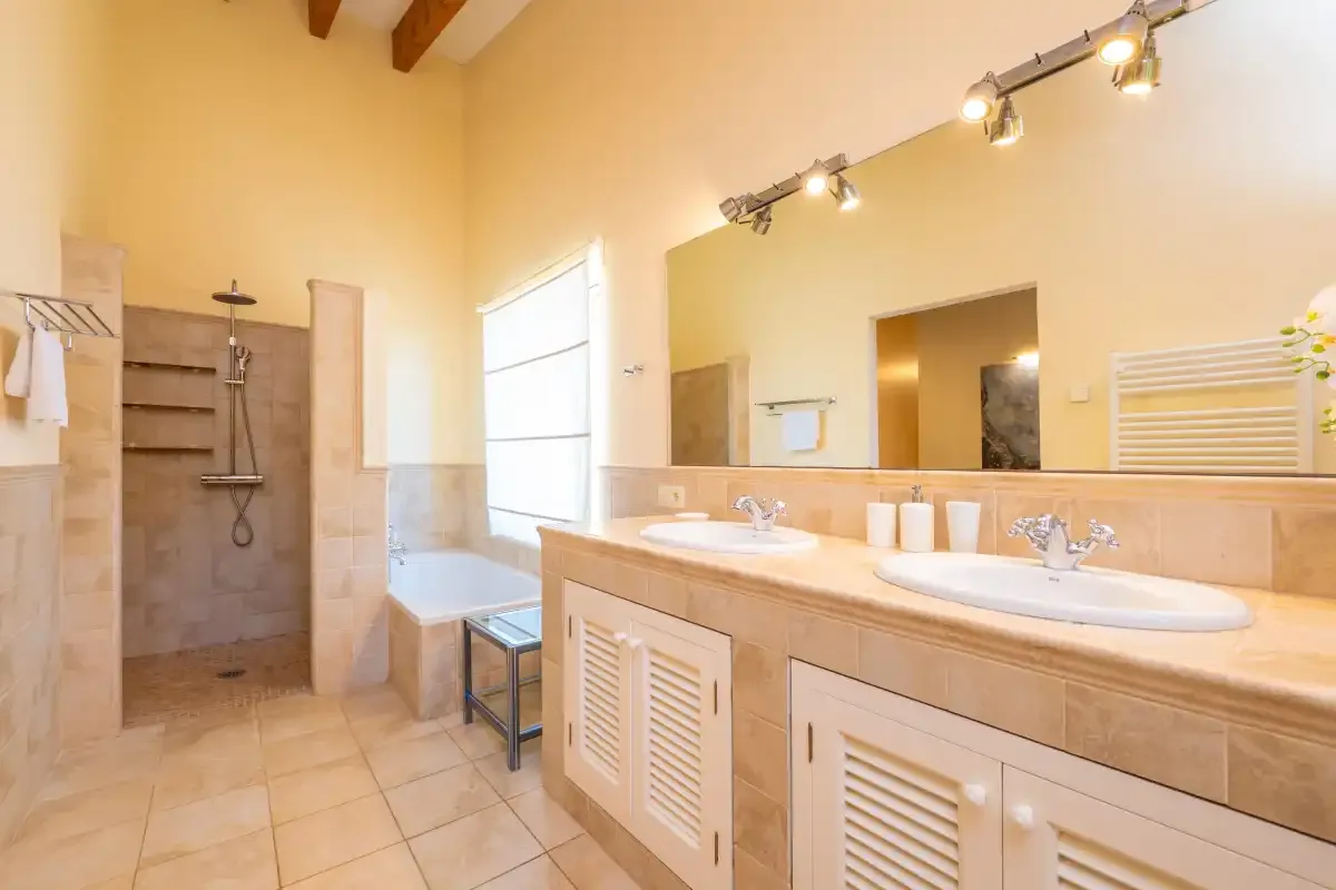 Un baño amplio con ducha, dos lavabos y un mueble de tocador largo.